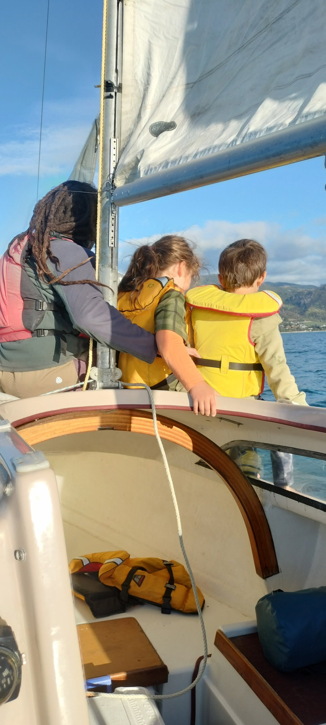 Family in lifejackets looking out from the cockpit toward the Golden Bay coast